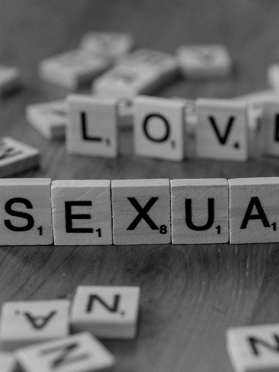 Holzbuchstabensteine mit den Buchstaben „Liebe“ und „Sexualität“ auf einem Holztisch.